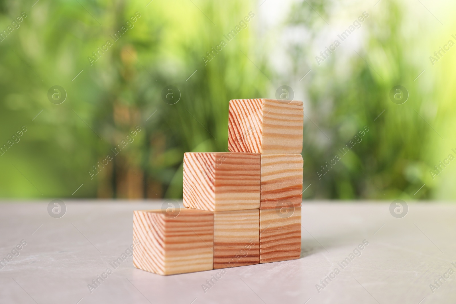 Photo of Many wooden cubes on light grey table outdoors