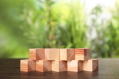 Photo of Many blank wooden cubes on table outdoors