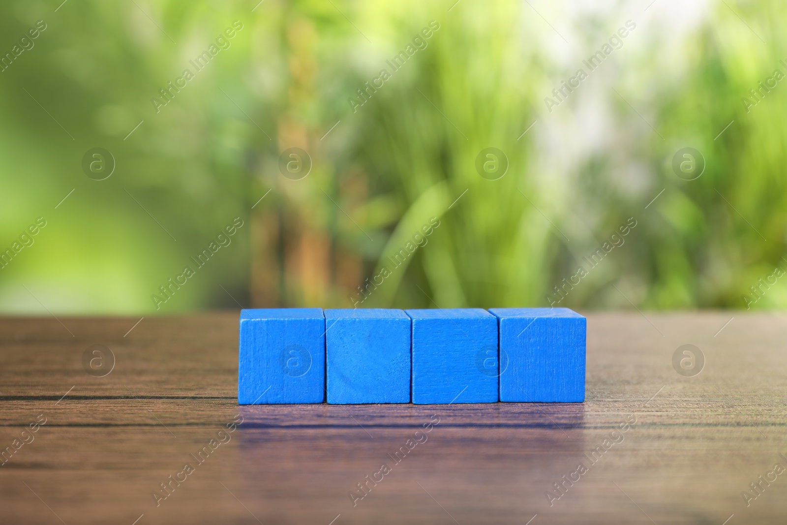 Photo of Many blank colorful cubes on wooden table outdoors