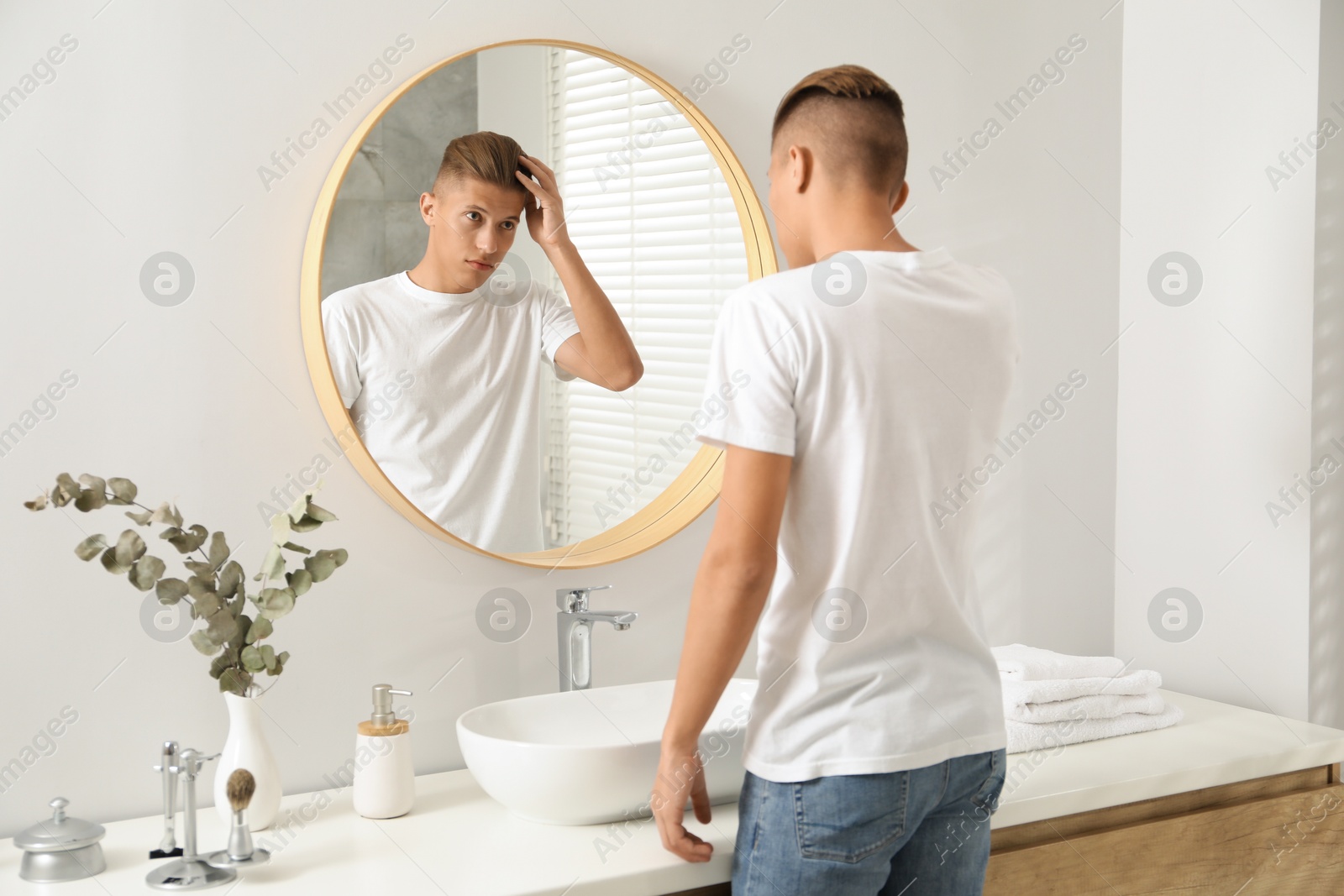 Photo of Handsome man looking at mirror in bathroom