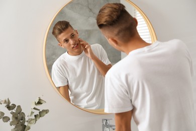 Handsome man looking at mirror in bathroom