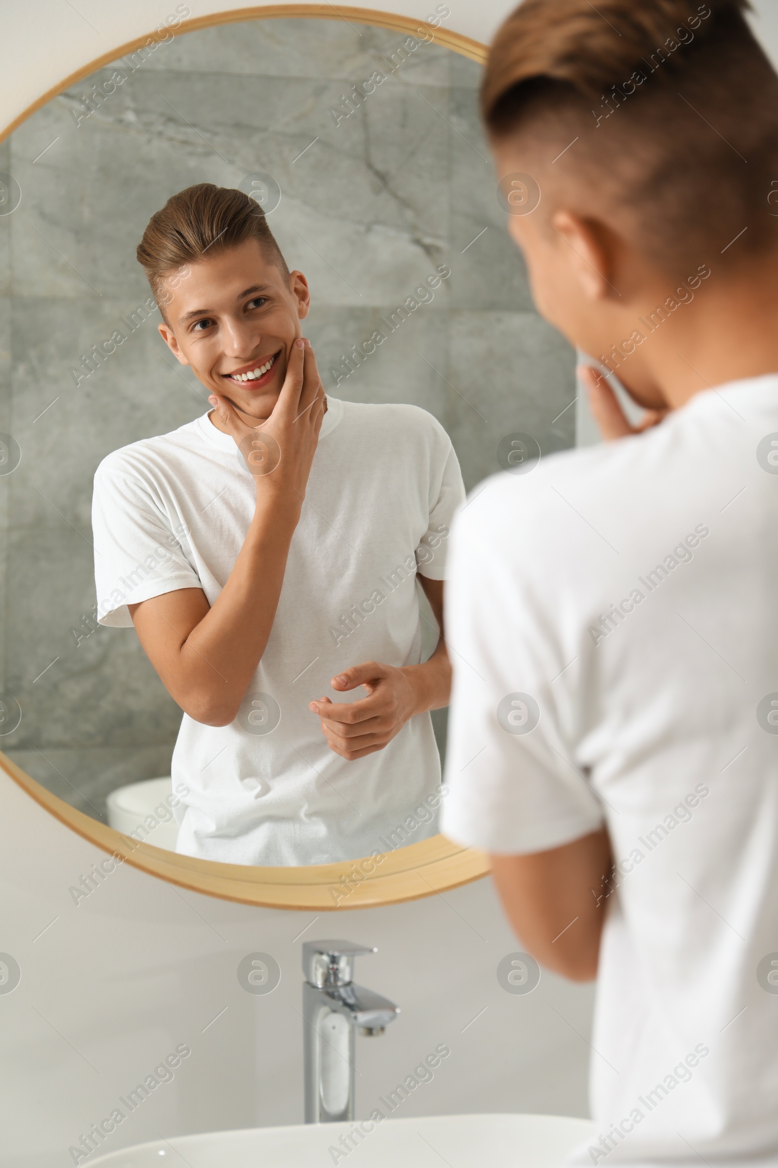 Photo of Handsome man looking at mirror in bathroom