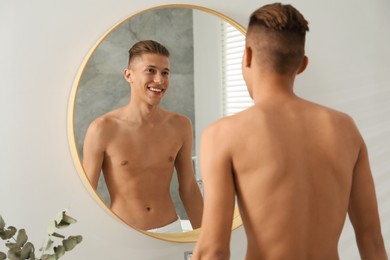 Handsome man looking at mirror in bathroom