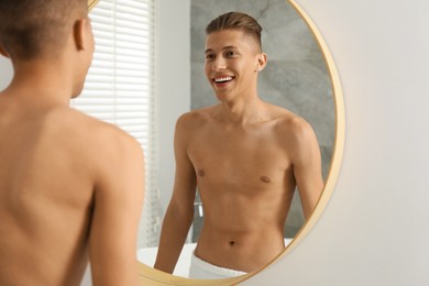 Photo of Handsome man looking at mirror in bathroom