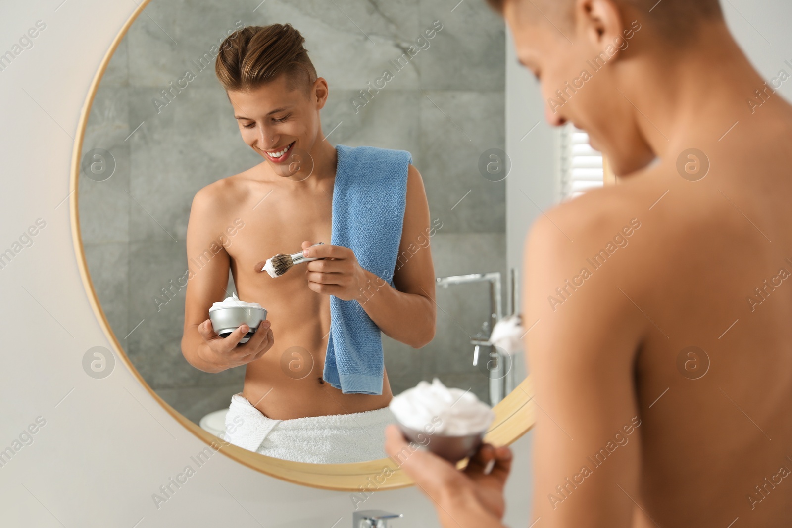 Photo of Handsome man applying shaving foam near mirror in bathroom