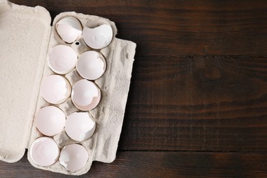 Photo of Broken eggshells in carton on wooden table, top view. Space for text