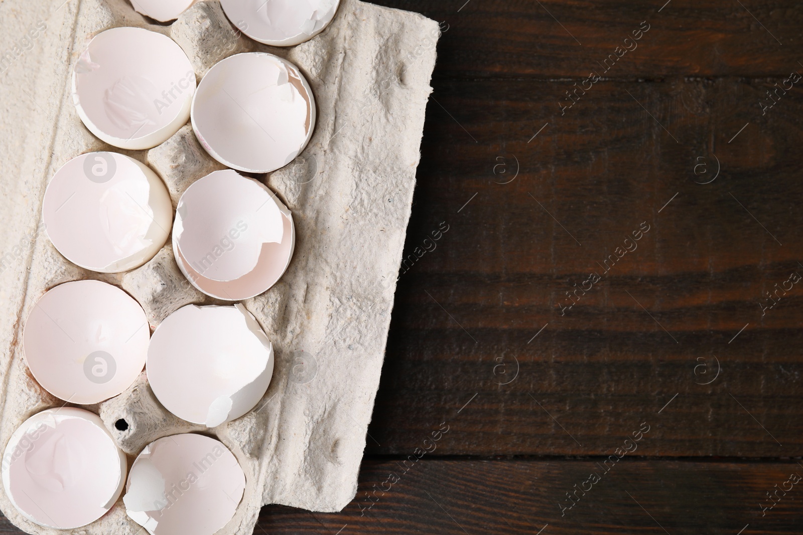 Photo of Broken eggshells in carton on wooden table, top view. Space for text