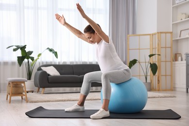 Beautiful pregnant woman doing exercises on fitball at home