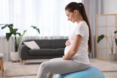 Beautiful pregnant woman doing exercises on fitball at home