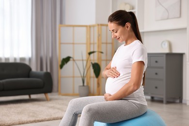 Beautiful pregnant woman doing exercises on fitball at home