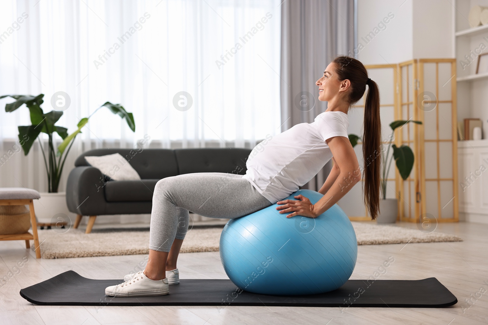 Photo of Beautiful pregnant woman doing exercises on fitball at home