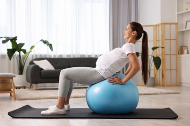 Beautiful pregnant woman doing exercises on fitball at home