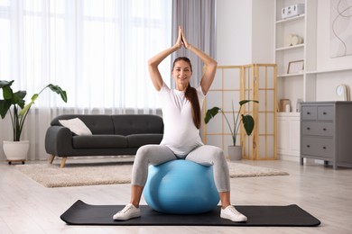 Beautiful pregnant woman doing exercises on fitball at home