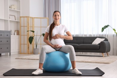 Beautiful pregnant woman doing exercises on fitball at home