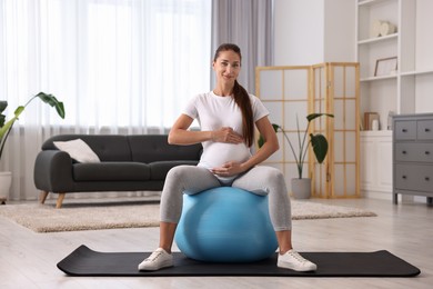 Beautiful pregnant woman doing exercises on fitball at home