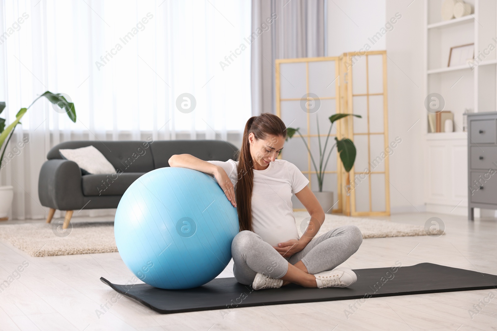 Photo of Beautiful pregnant woman with fitball on exercise mat at home