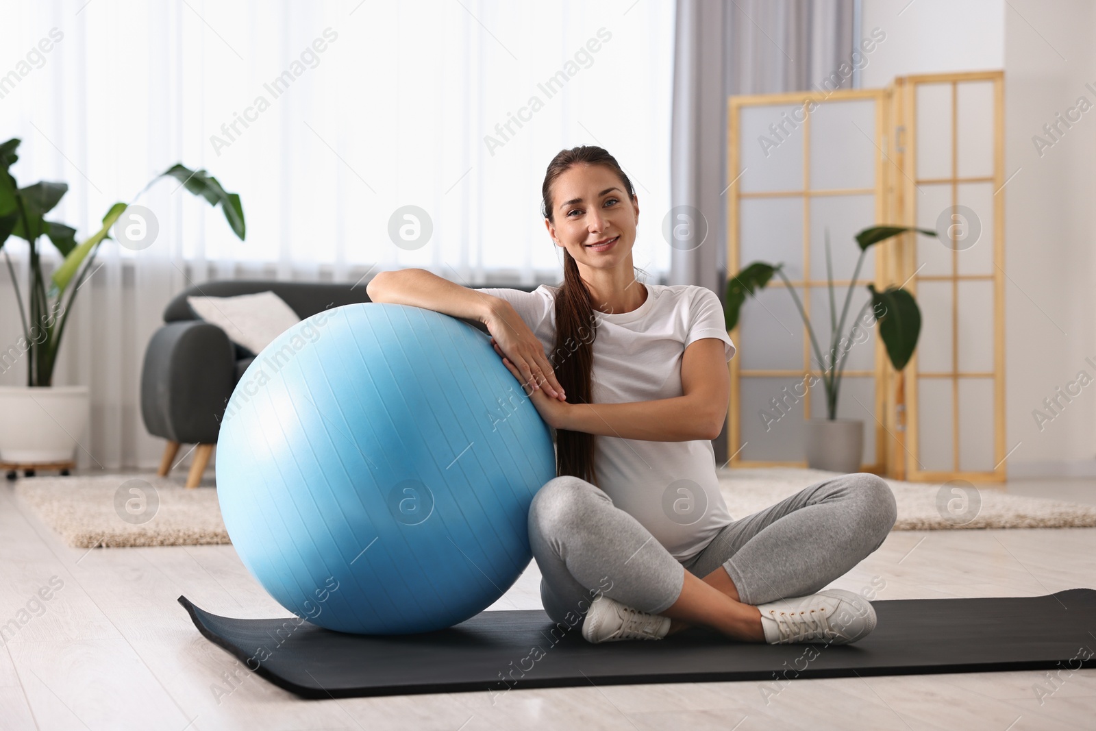 Photo of Beautiful pregnant woman with fitball on exercise mat at home