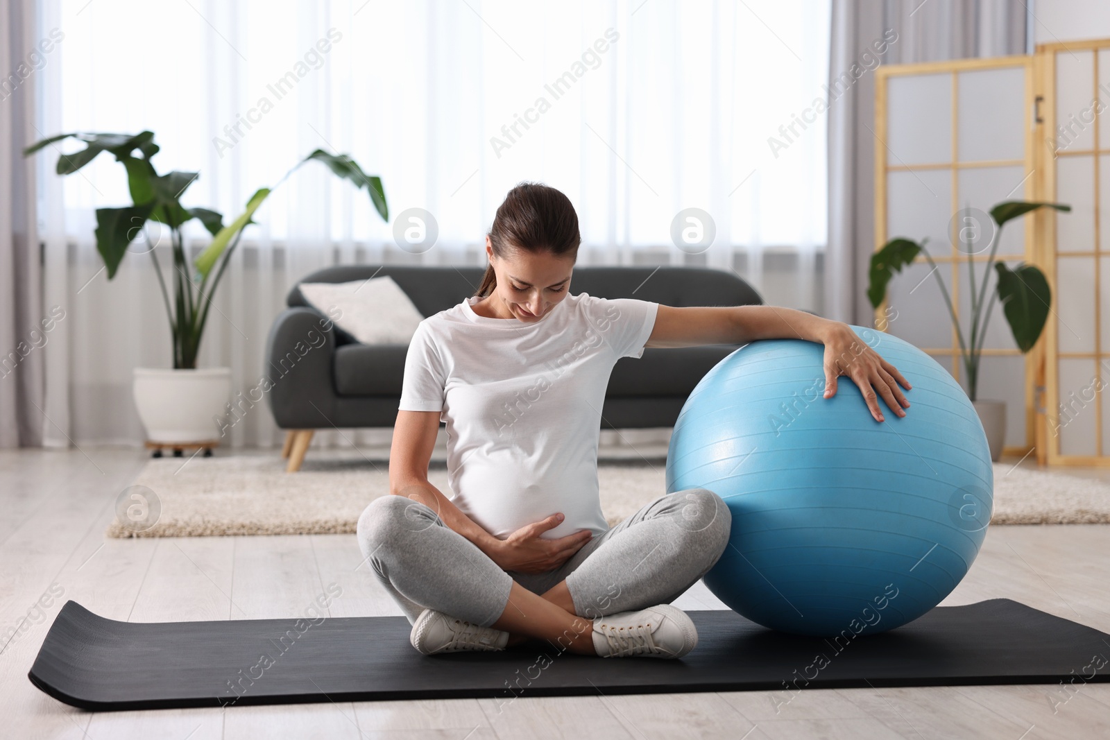 Photo of Beautiful pregnant woman with fitball on exercise mat at home