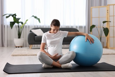 Photo of Beautiful pregnant woman with fitball on exercise mat at home