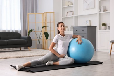 Beautiful pregnant woman doing exercises with fitball at home