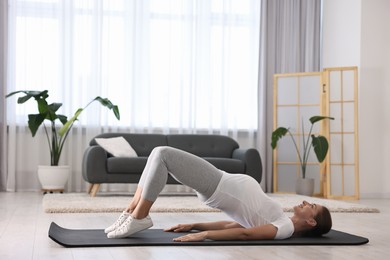 Beautiful pregnant woman doing stretching exercises on mat at home