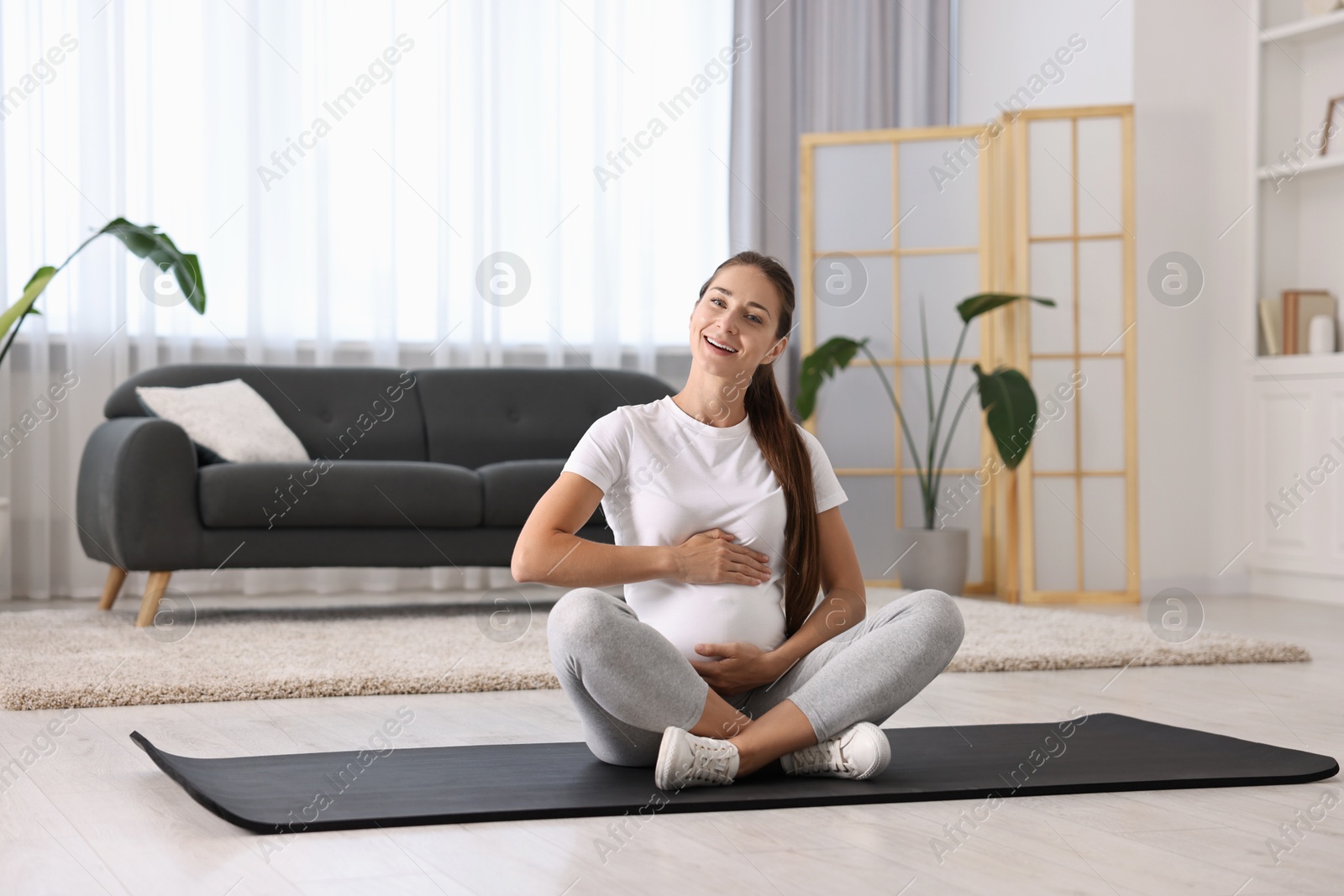 Photo of Beautiful pregnant woman on exercise mat at home