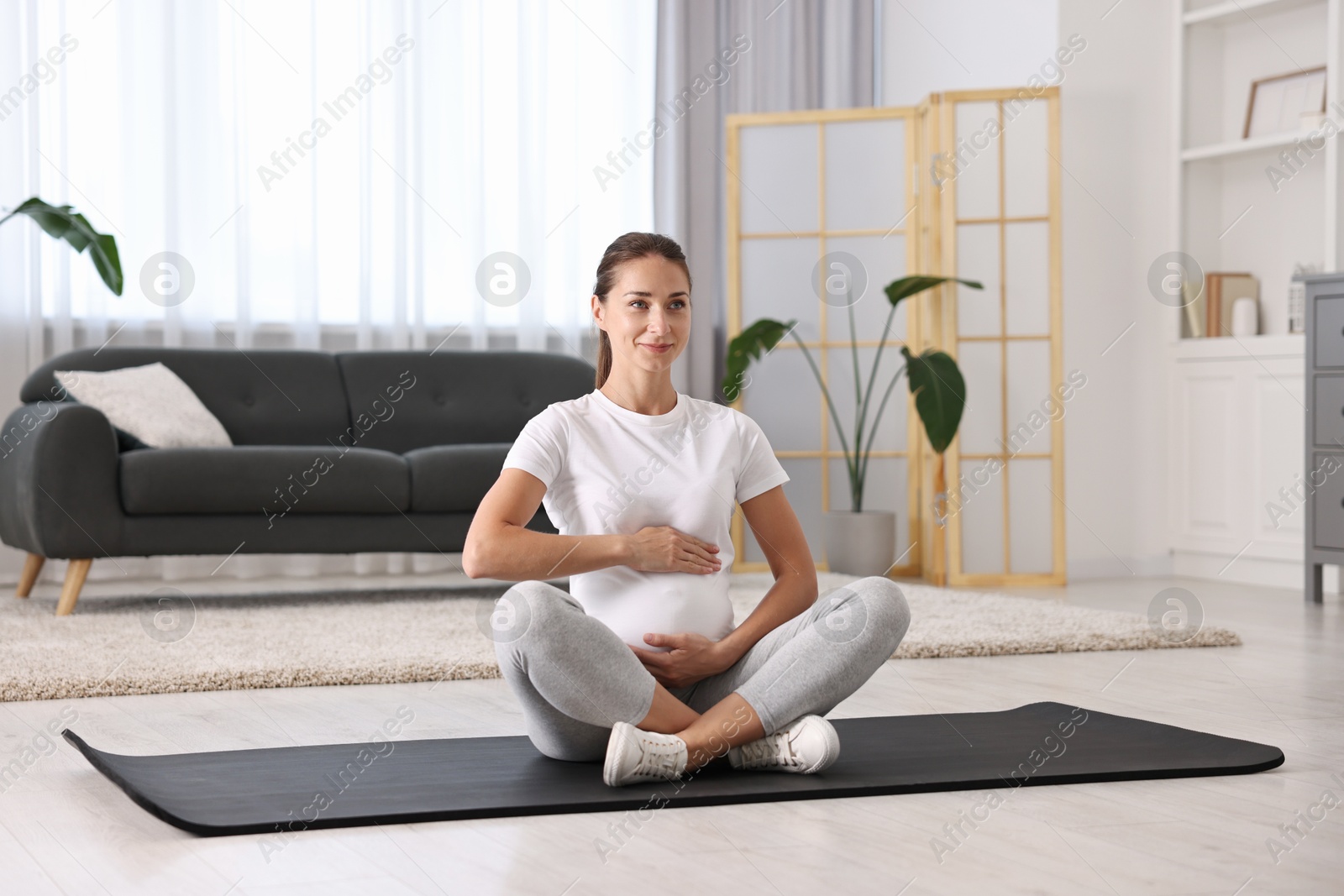 Photo of Beautiful pregnant woman on exercise mat at home