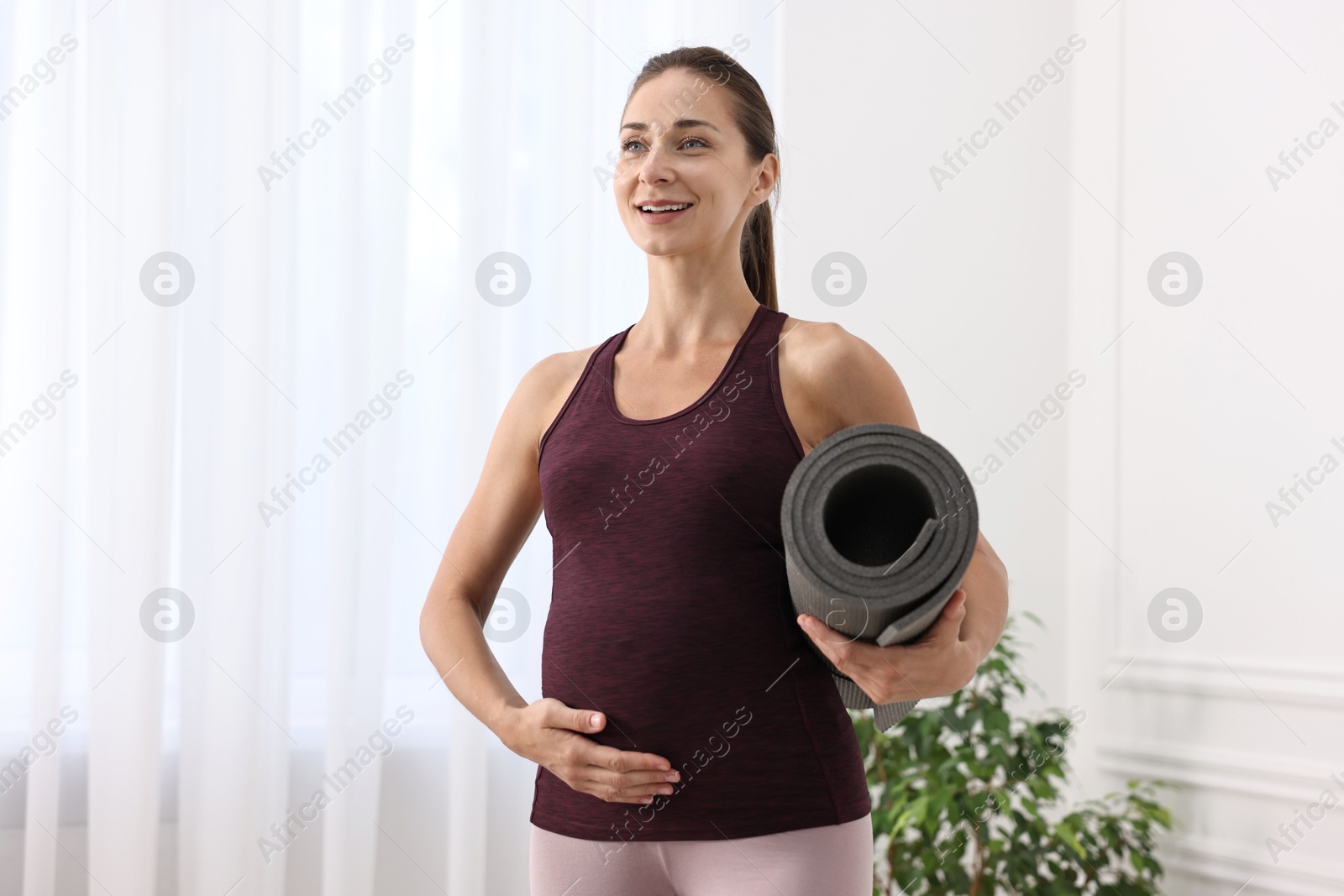 Photo of Beautiful pregnant woman with exercise mat at home