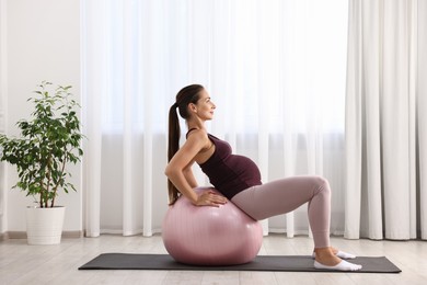 Beautiful pregnant woman doing exercises on fitball at home