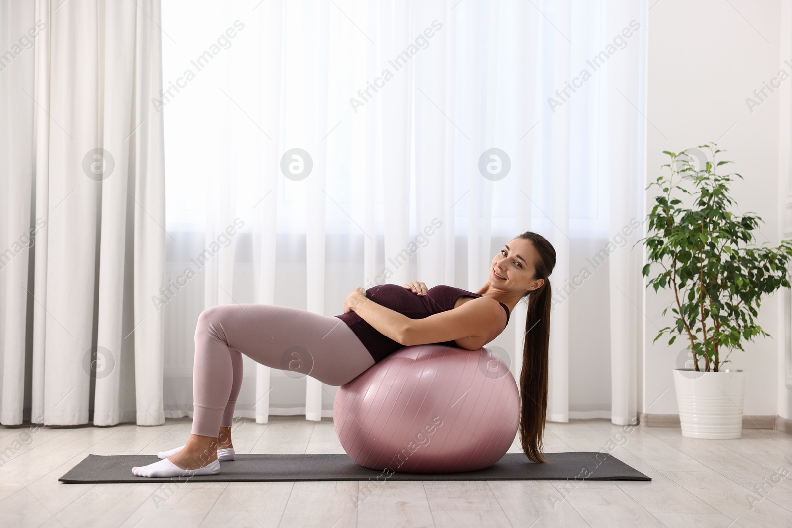 Photo of Beautiful pregnant woman doing exercises on fitball at home