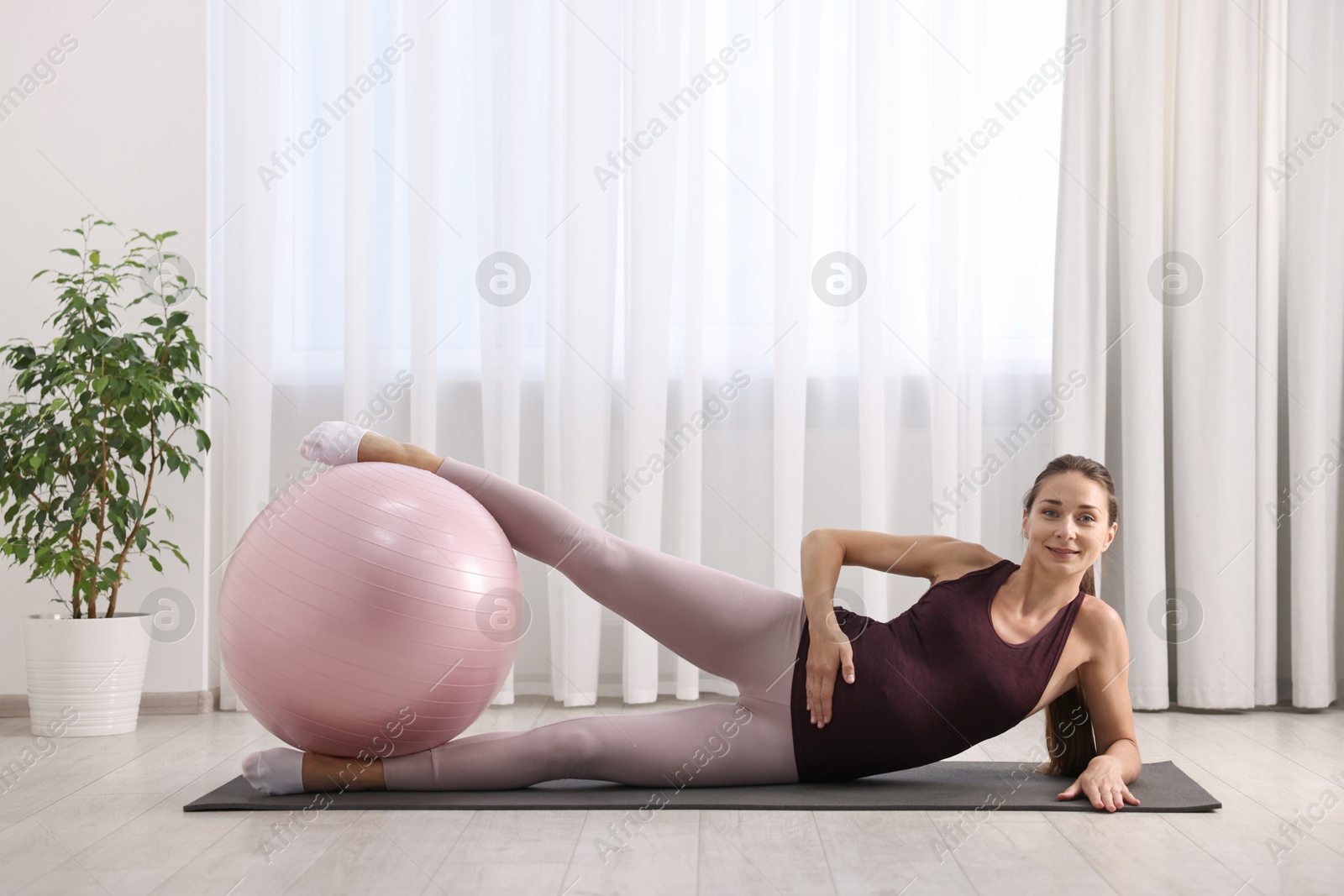 Photo of Beautiful pregnant woman doing exercises with fitball on mat at home