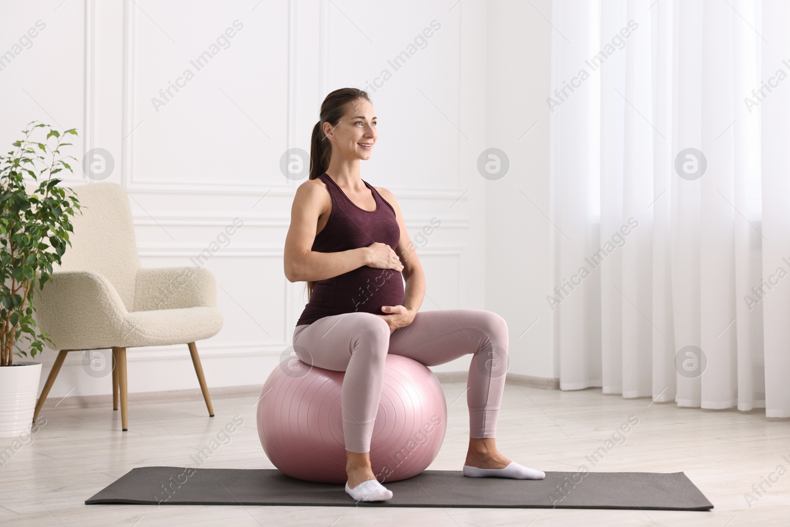 Photo of Beautiful pregnant woman doing exercises on fitball at home