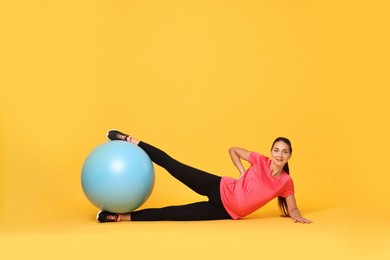 Beautiful pregnant woman doing exercises with fitball on yellow background