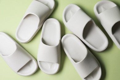 Pairs of slippers on green background, top view