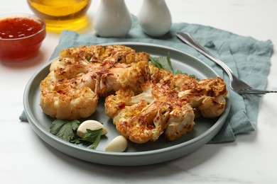 Photo of Delicious baked cauliflower steaks with garlic and parsley on white table, closeup