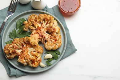 Photo of Delicious baked cauliflower steaks with garlic and parsley on white table, flat lay. Space for text