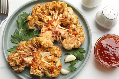 Photo of Delicious baked cauliflower steaks with garlic and parsley on white table, flat lay