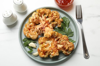 Photo of Delicious baked cauliflower steaks with garlic and parsley on white table, flat lay