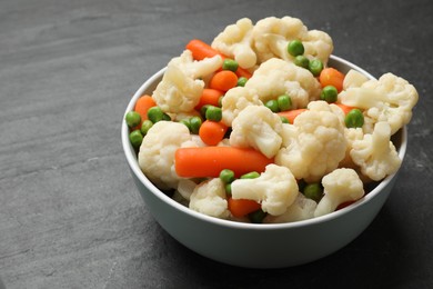 Photo of Tasty cauliflower with baby carrots and green peas on black table, closeup. Space for text