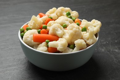 Photo of Tasty cauliflower with baby carrots and green peas on black table, closeup