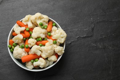 Photo of Tasty cauliflower with baby carrots and green peas on black table, top view. Space for text