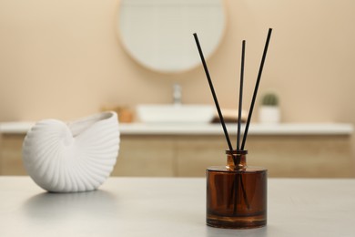 Reed diffuser and beautiful shell shaped vase on table in bathroom. Space for text