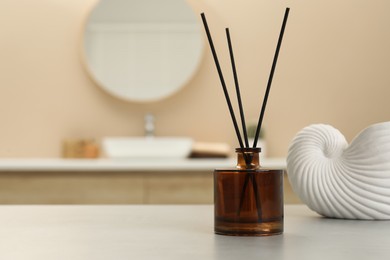 Reed diffuser and beautiful shell shaped vase on table in bathroom. Space for text