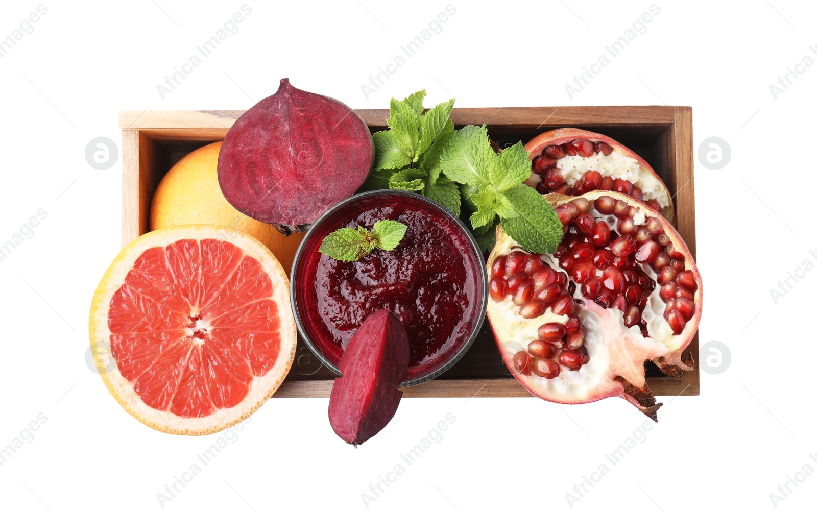 Photo of Glass of tasty beetroot smoothie, fresh vegetables, fruits and mint in wooden box isolated on white, top view. Vegan drink