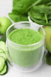 Tasty green smoothie in glass and products on white tiled table, closeup