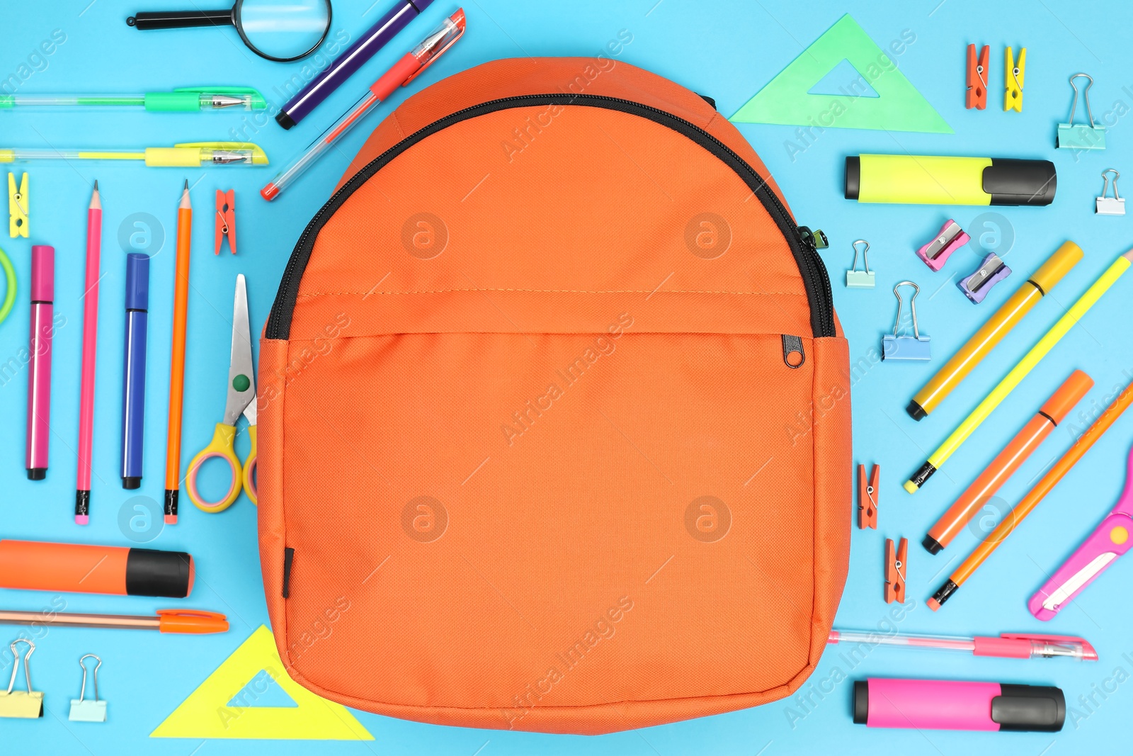 Photo of Backpack and different school supplies on light blue background, flat lay