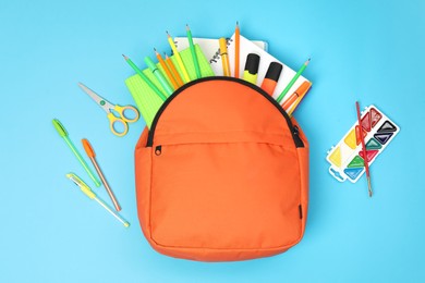 Backpack and different school supplies on light blue background, flat lay