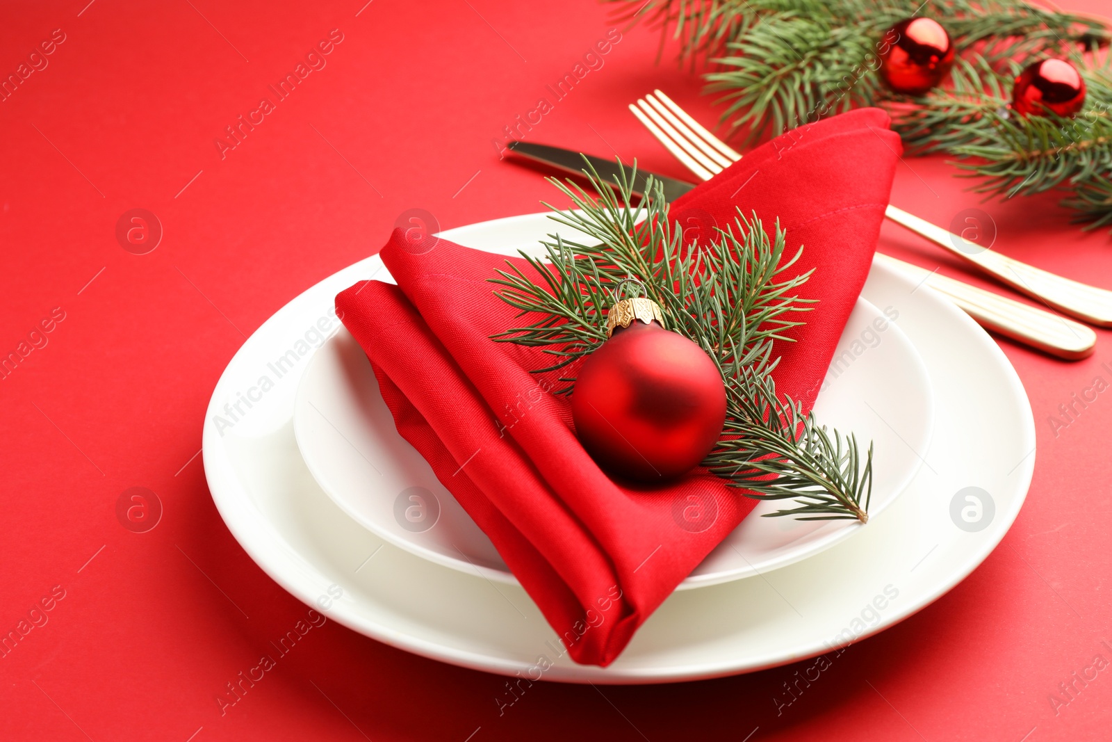 Photo of Beautiful Christmas setting with plates, elegant cutlery and festive decor on red table