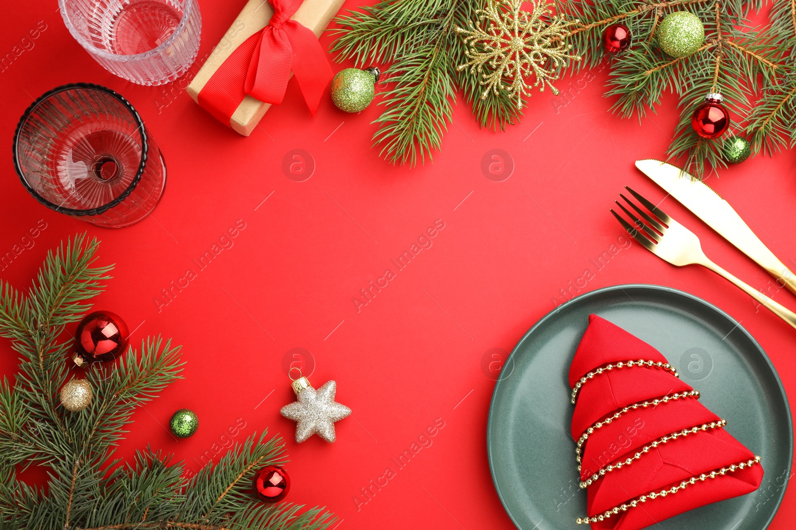 Photo of Beautiful Christmas setting with plate, elegant cutlery and festive decor on red table, flat lay. Space for text