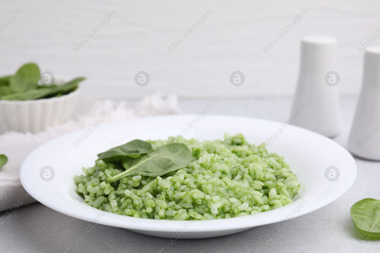 Photo of Delicious spinach risotto on light grey table, closeup